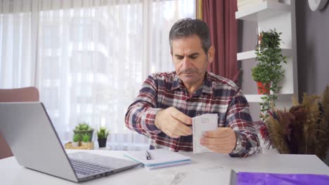 economía doméstica. hombre de familia mirando deudas y facturas y desesperado.