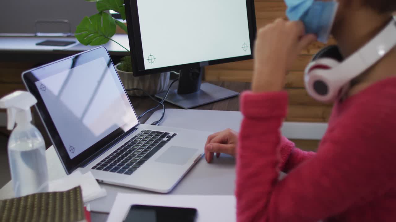 sección media de una mujer afroamericana teniendo un video chat en su computadora portátil en una oficina moderna