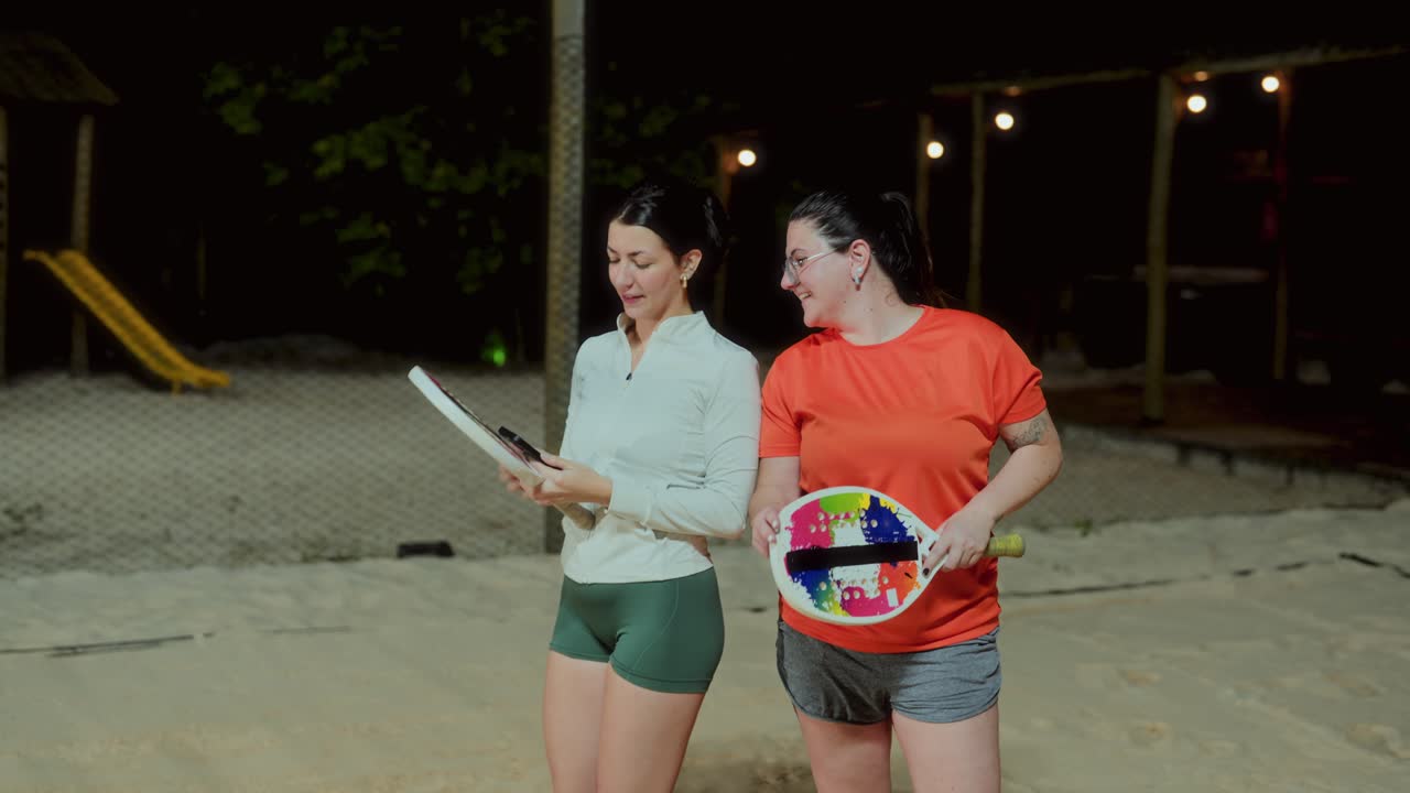 Women Playing Beach Tennis and Taking Selfies at Night