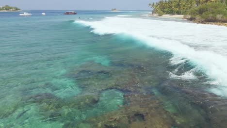 una ola rueda en el agua clara de maldivas cerca de la costa