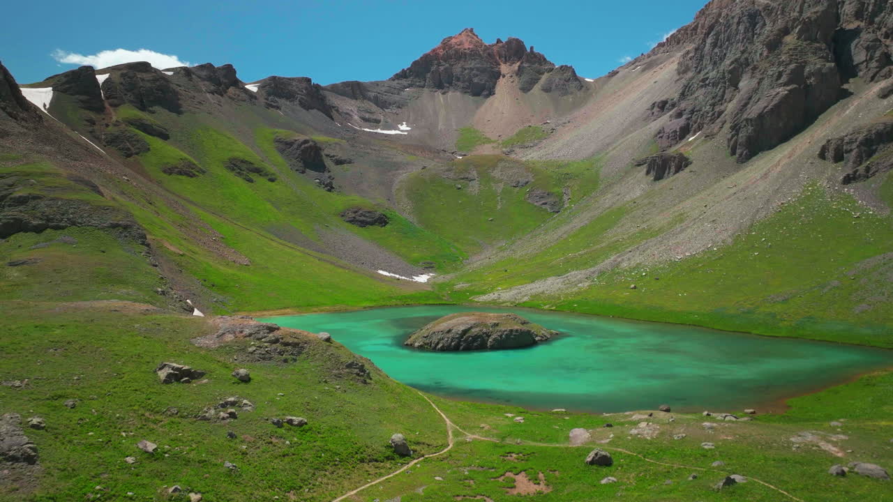 Cinematic aerial drone high elevation dreamy heavenly Island Lake Silverton Ice Lake Basin unreal Caribbean aqua blue Silverton Colorado lush green summer snow melting Rocky Mountains slowly backwards