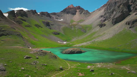 Filmische-Luftdrohne-In-Großer-Höhe,-Verträumt,-Himmlische-Insel,-See,-Silverton-Eis,-Seebecken,-Unwirklich,-Karibisches-Aquablau,-Silverton,-Colorado,-üppiges-Grün,-Sommerschnee,-Schmelzende-Felsige-Berge,-Langsam-Rückwärts