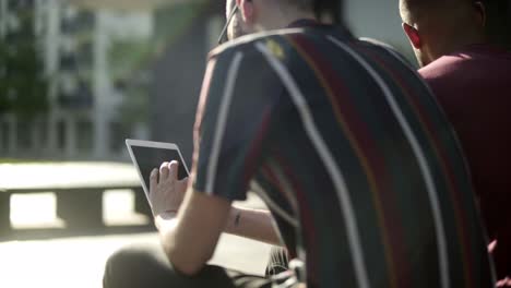 back view of young bearded man using tablet