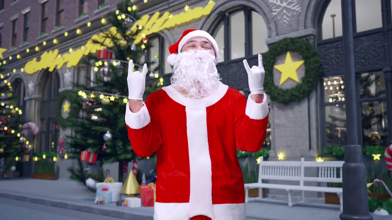 아시아 산타클로스가 크리스마스 밤에 손으로 록 앤 롤 제스처를 보여줍니다.