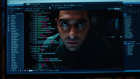 man's intense reflection on a computer screen displaying code