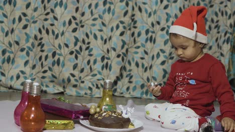 cute-infant-enjoying-Christmas-eve-celebration-at-home-at-night-from-different-angle