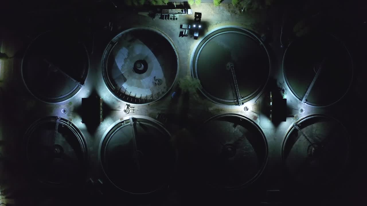 vista aérea nocturna de una moderna planta de tratamiento de aguas residuales con piscinas redondas para la limpieza de aguas residuals