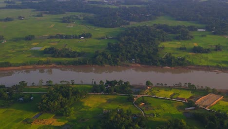 aerial view of surma river running through rural green countryside fields in sylhet, bangladesh