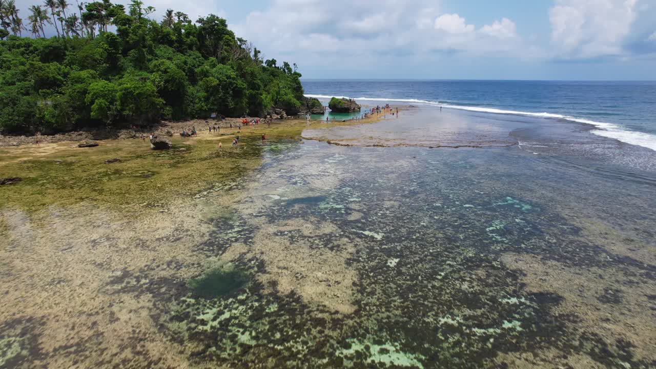 Video drone 4K che sorvola una donna in piedi nelle piscine naturali rocciose di Magpupungko Rock Pools sull'isola di Siargao nelle Filippine.