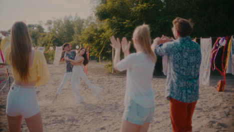 Young-friends-clapping-and-cheerful-couple-dancing-bachata-at-beach