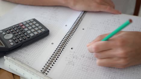 resolución manual de problemas algebraicos en un cuaderno de matemáticas con calculadora científica al lado