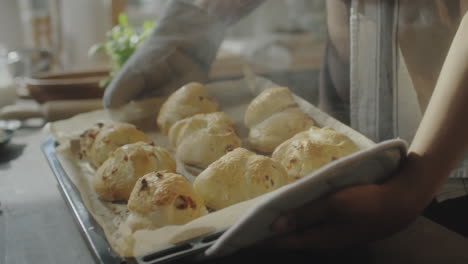 taking freshly baked buns out of the oven