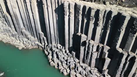 Aerial-drone-pan-shot-from-right-to-left-flying-over-rocky-column-shaped-in-Studlagil-Canyon-in-east-Iceland,-Europe-on-a-sunny-day