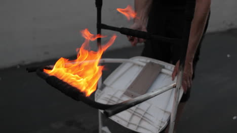 a street performer demonstrates his ability to juggle flaming torches whilst balancing a flaming chair on his forehead