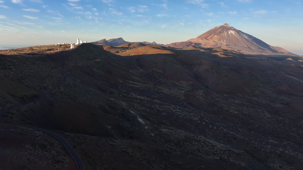 Una strada tortuosa passa accanto all'osservatorio del Teide con il vulcano Teide sullo sfondo. Isole Canarie. Tenerife. Video aereo.