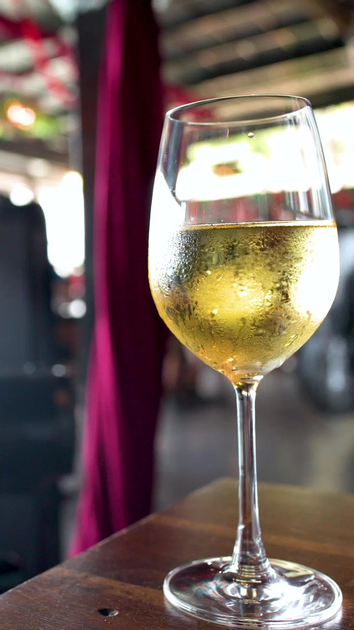 Primo piano di un bicchiere di vino bianco ghiacciato su un tavolo di legno