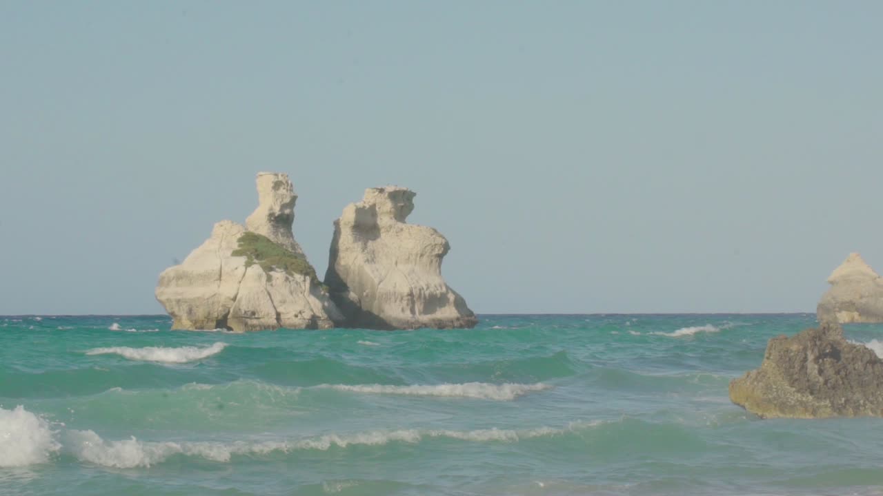 широкоформатный снимок двух сестер в замедленном режиме на фоне чистого голубого неба и бирюзовой воды