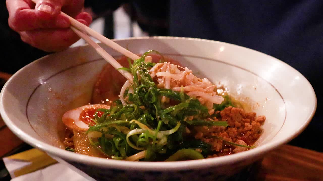 가락이 라멘 그에서 누들을 들어 올리고 있다