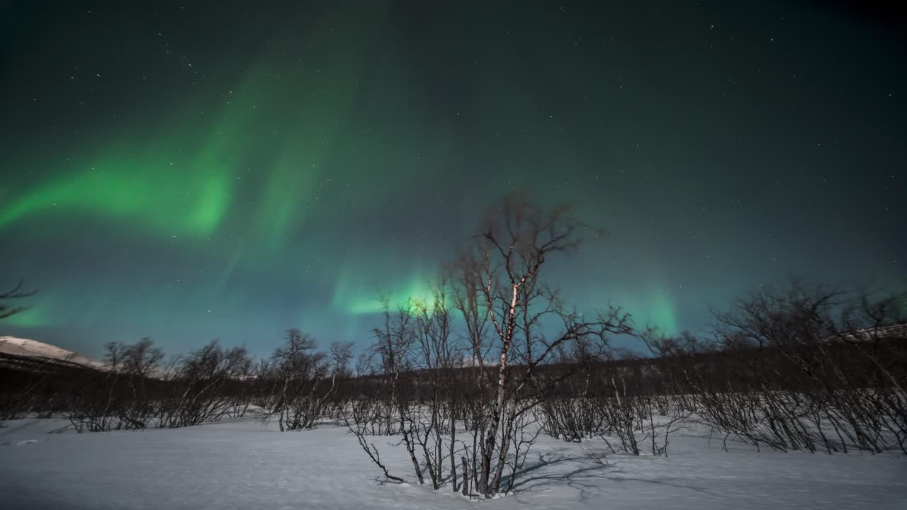 Northern lights dancing over a snowy landscape in Kilpisjärvi, captured in timelapse