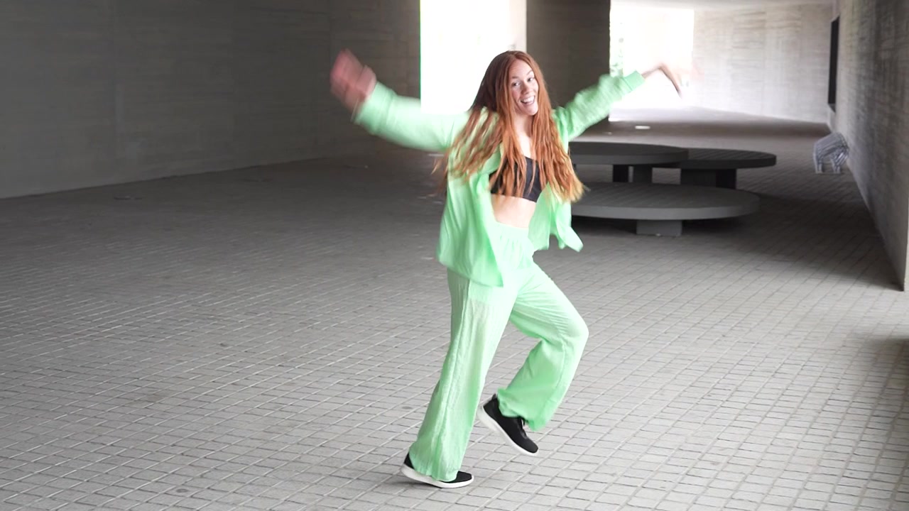 都会のトンネルで、緑の服を着た女性が自由を表現するようにエネルギッシュに踊る。