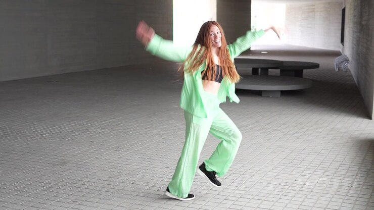 Woman in green clothes energetically dances in an urban tunnel expressing freedom