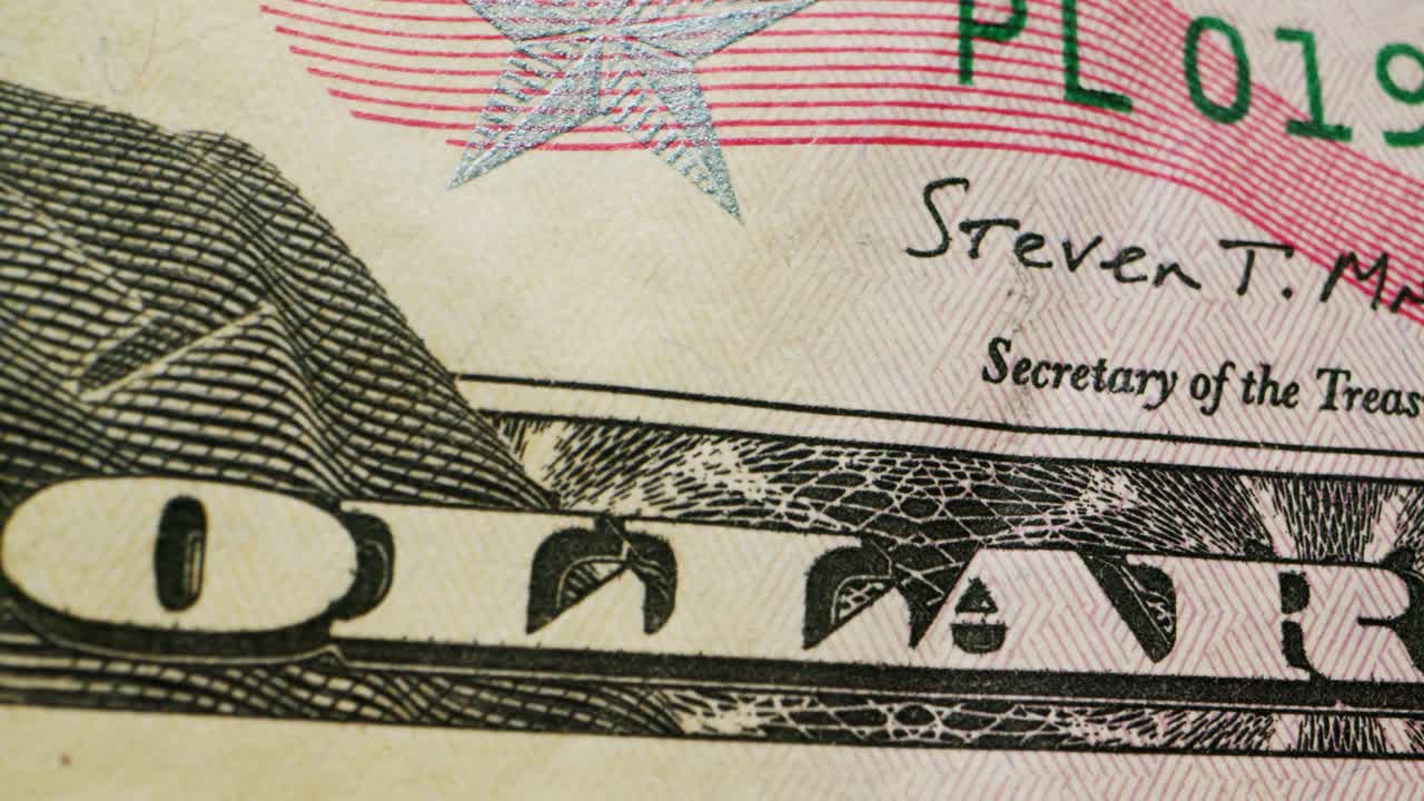 A closeup view of a fifty dollar bill on a polished wooden table, highlighting its intricate design
