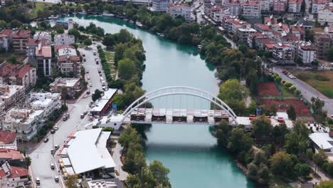 aerial view orbiting archway bridge over the curving manavgat river in the city centre of the antalya region, turkey