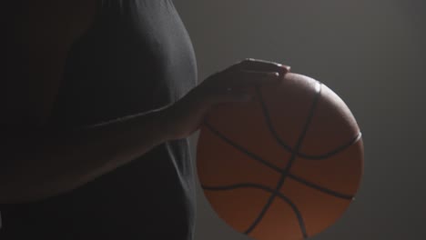 close up studio shot of male basketball player dribbling ball against dark background