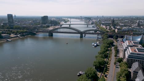 Cologne,-North-Rhine-Westphalia,-Germany---aerial-bird-drone-flight-over-the-Rhein-in-Köln-with-Hohenzollern-Bridge-and-Ships-on-a-summer-day-in-2022