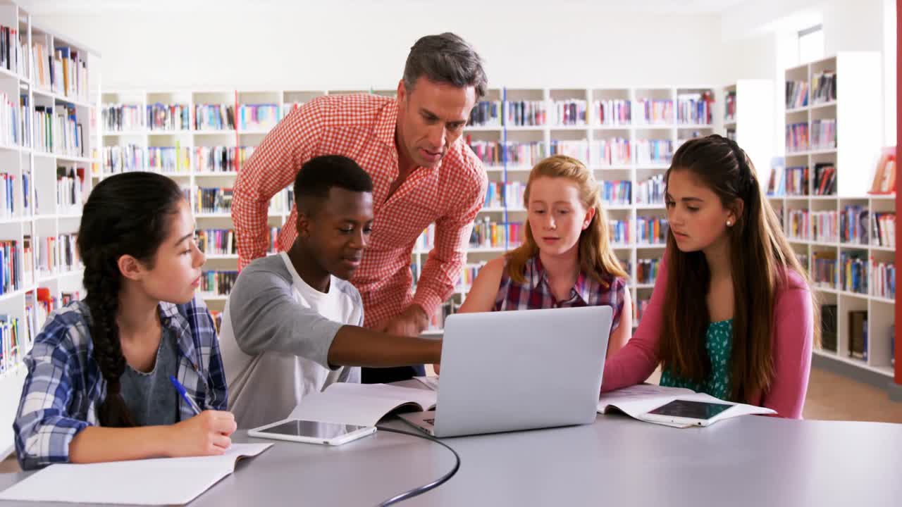 maestro ayudando a los escolares en el portátil 4k