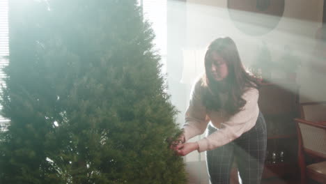 woman setting up a christmas tree indoors with bright sunlight