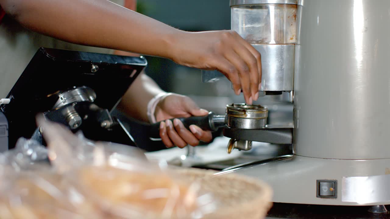 Barista's hands are aligning portafilter at bar pressing dose and leveling grounds for even shot