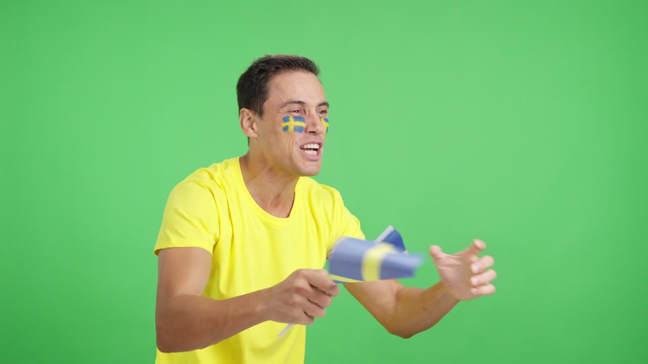 Man cheering for Sweden waving a national flag looking away