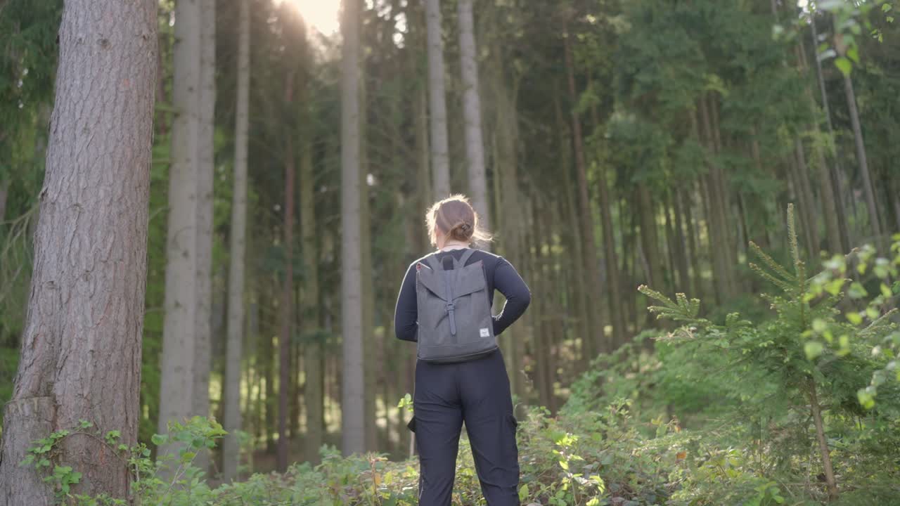 Girl adventurer stands and admires with wonder the forest landscape illuminated by the spring sun
