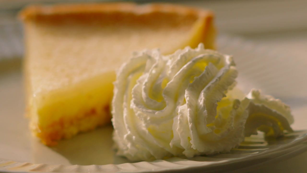 Přední pohled na klasický francouzský Tarte au Citron na talíři se šlehačkou. Ideální pro aplikace s jídlem, montáže pro sociální média, promo akce luxusních restaurací, videa s dezertní tematikou. 4K.
