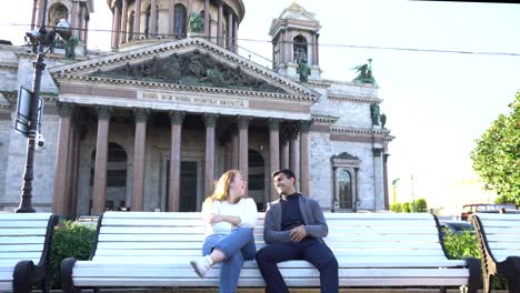 couple sitting on a bench in front of a beautiful church