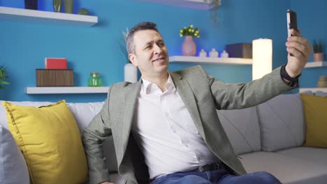 conceited mature man taking selfie on smartphone alone at home.