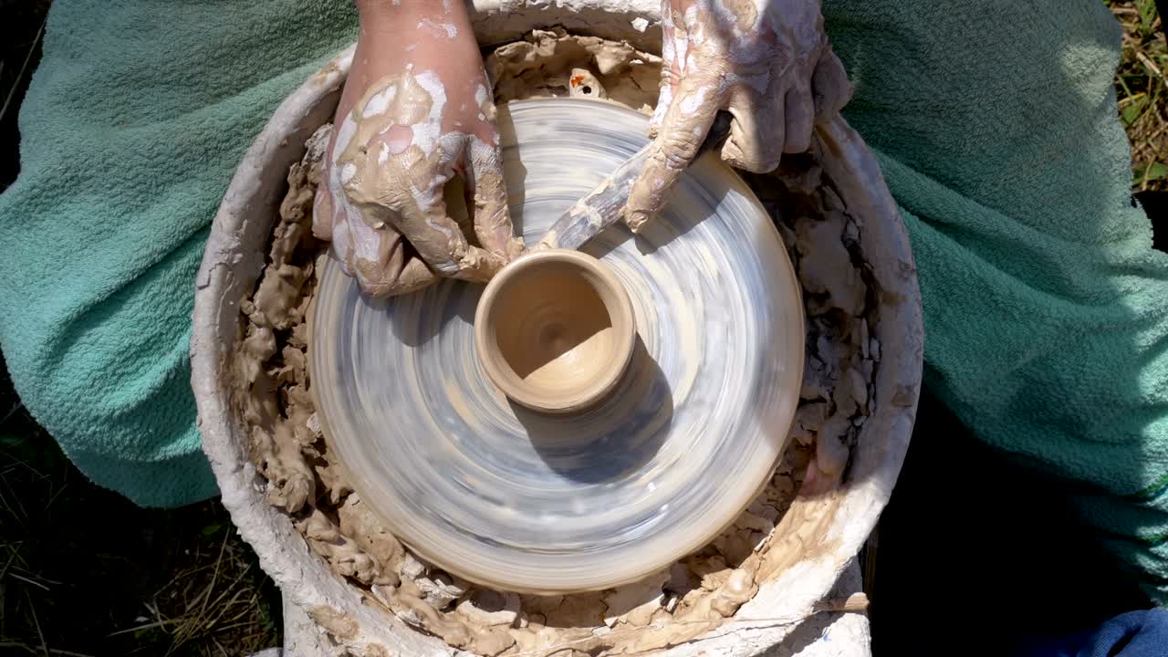 las manos del maestro alfarero y el jarrón de barro en la rueda del alfarero