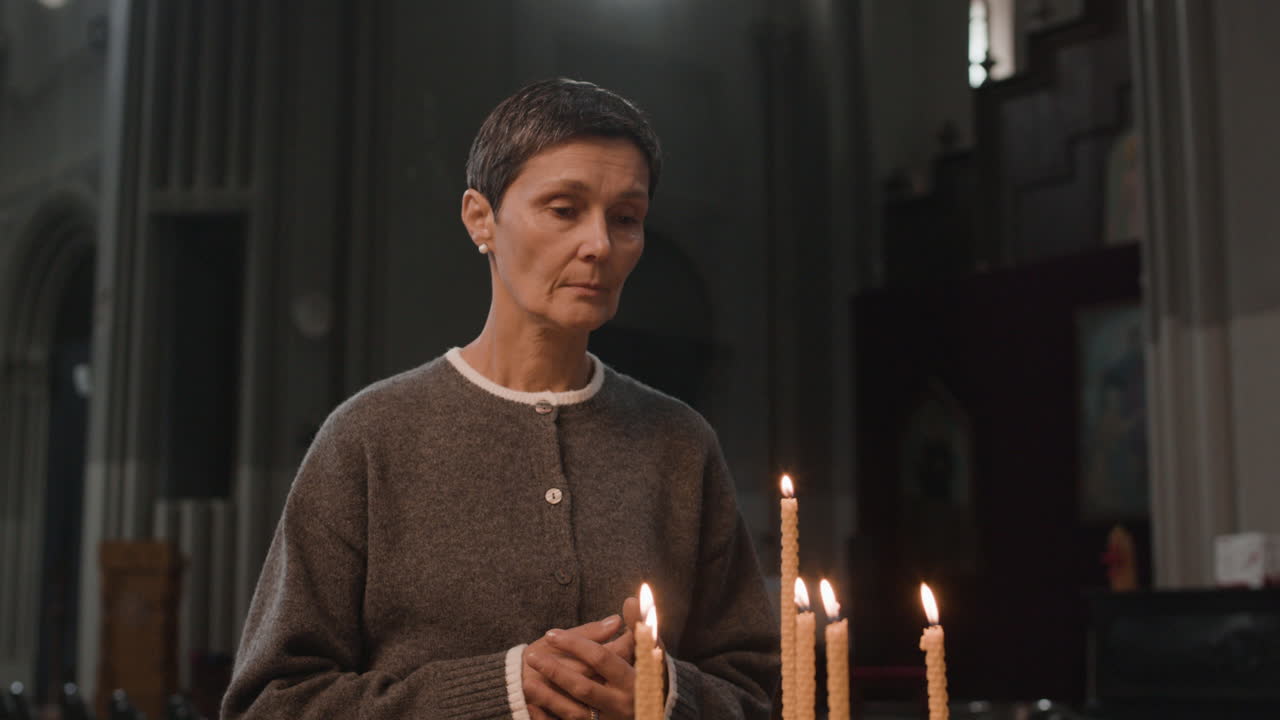 Woman praying in a church with candles
