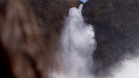 cascada en cámara lenta sobre el hombro de una chica de cabello castaño en un terreno montañoso rocoso