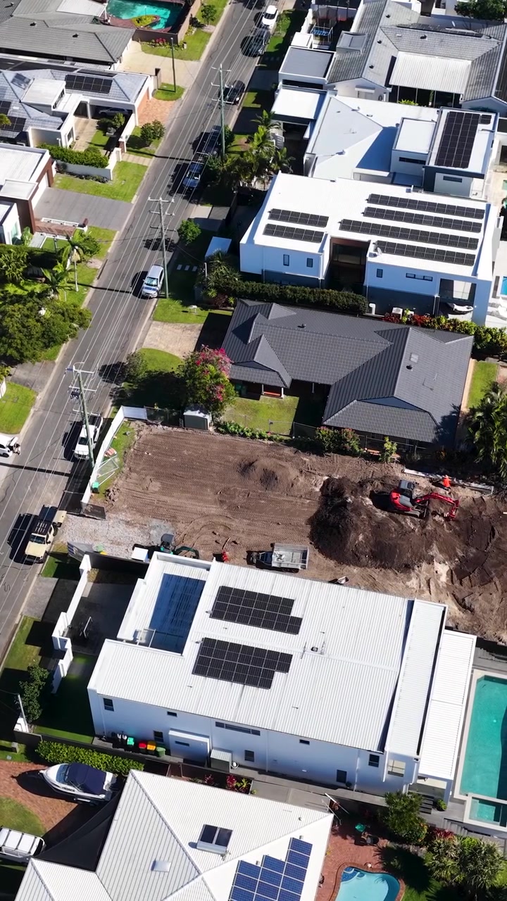 High-angle drone shot captures modern residential architecture and active construction in a coastal neighborhood.