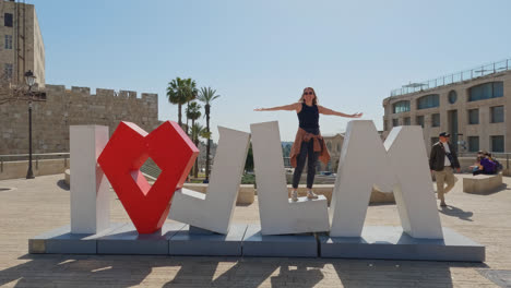 Happy-woman-standing-on-I-love-Jerusalem-sign-on-sunny-day