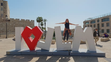 happy woman standing on i love jerusalem sign on sunny day