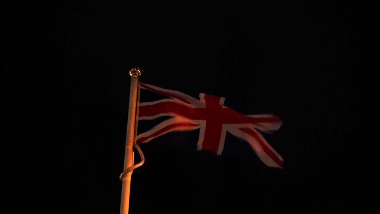 union jack británica - bandera británica que sopla en el viento en la noche