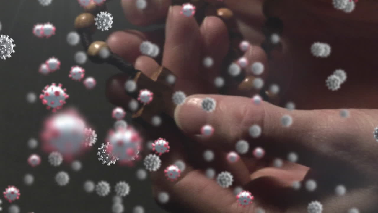 células de covid-19 moviéndose contra las manos orando y sosteniendo el rosario