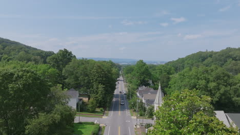 drone footage looking down a straight, tree-lined road in st. elmo, chattanooga, framed by forested hills and historic homes on either side