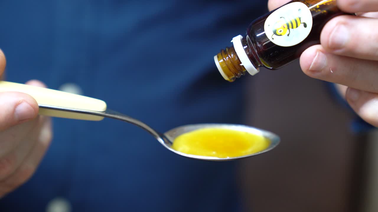 Adding Drops Of Propolis Extract On A Teaspoon On Honey. - closeup shot