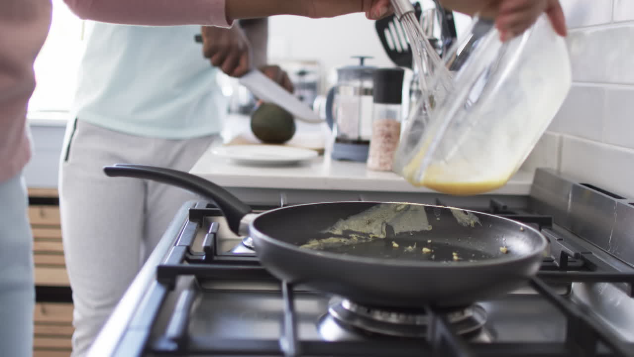 una pareja diversa está cocinando el desayuno juntos en una cocina moderna