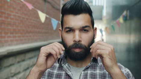 man adjusting beard in an urban alley