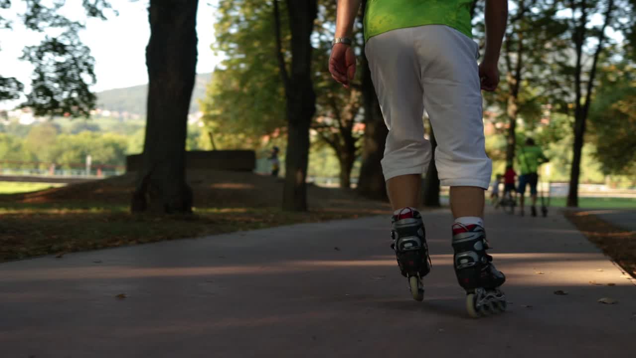 Nærbilde av en person som går på rulleskøyter gjennom en bypark.